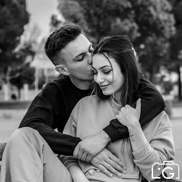 Black and white portrait of Lambros kissing Stella on the forehead, outdoors.
